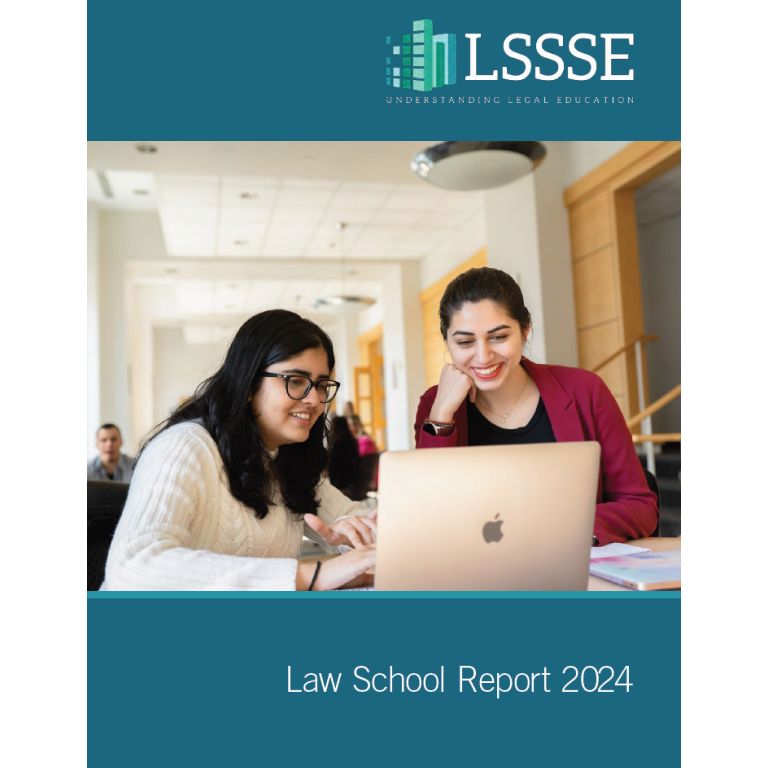 A book cover titled, "Law School Report 2024." The cover has a blue-gray top and bottom, with a photo in the middle of two law students looking at a laptop. A woman with glasses and a white sweater is looking at the screen, and a woman with a red jacket is leaning on her elbow and smiling at her. The "LSSSE" logo is at the top of the cover, and the title is at the bottom.